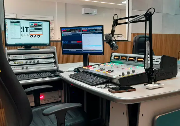 Mesa de som, computadores e microfone no estúdio da RITA FM
